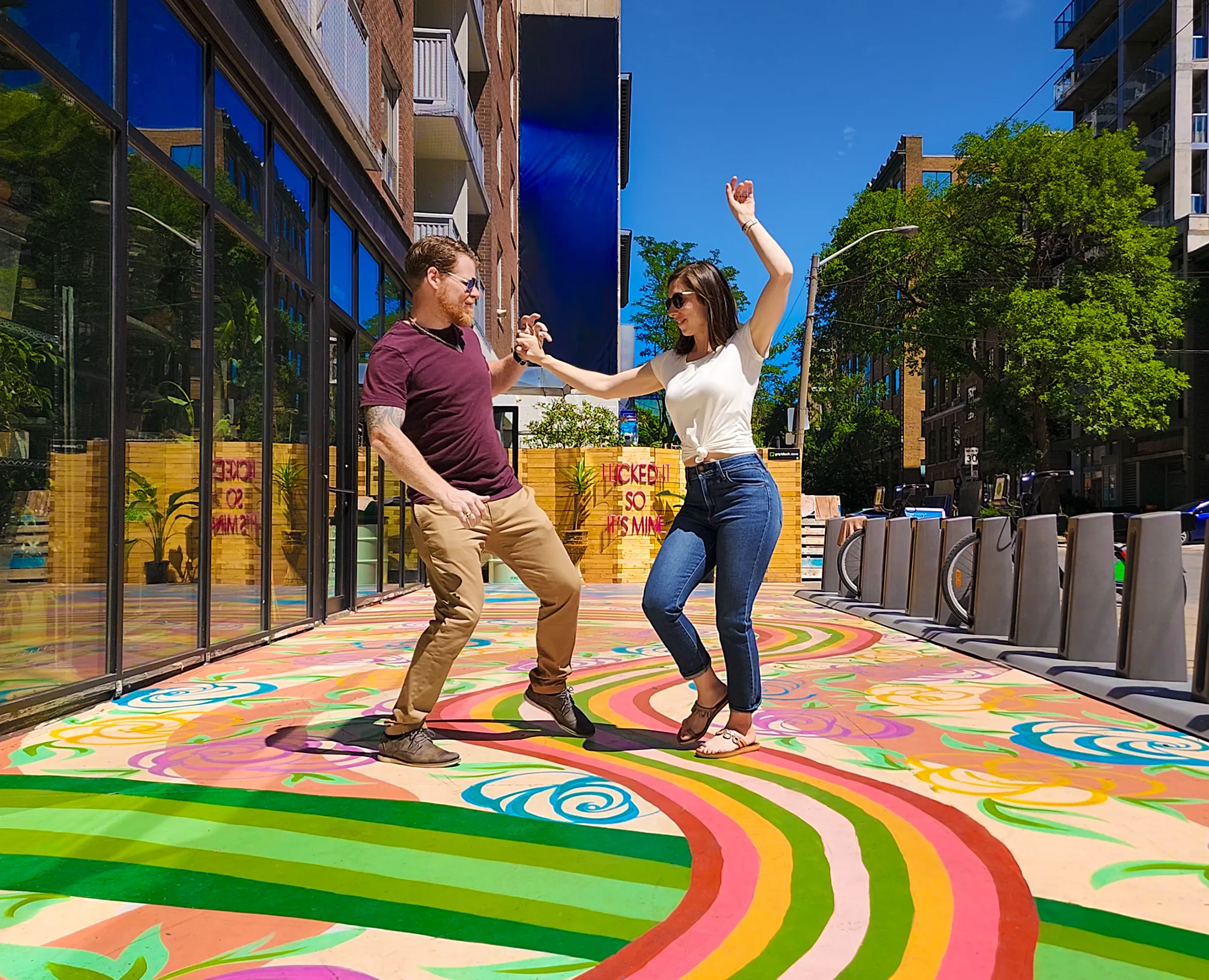Two people dancing together outdoors on a vibrant sidewalk.
